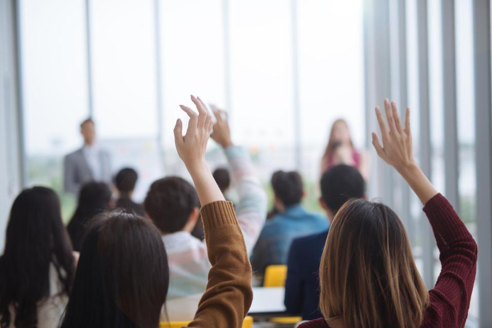 Raised up hands and arms of large group in seminar class room to agree with speaker at a seminar meeting room