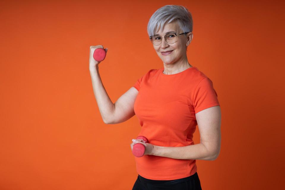 cheerful elderly woman in sportswear with dumbbells