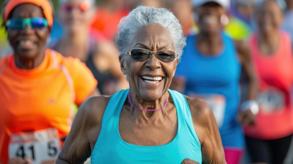 An elderly woman runs energetically in a community 5K event surrounded by enthusiastic runners