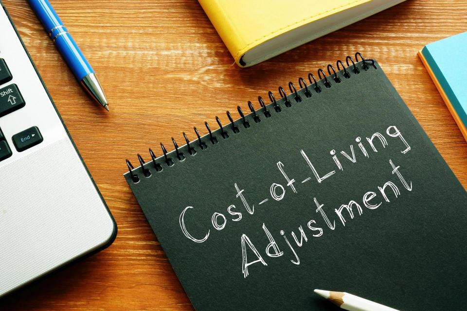 Cost of Living Adjustment written in chalk on a black notepad.
