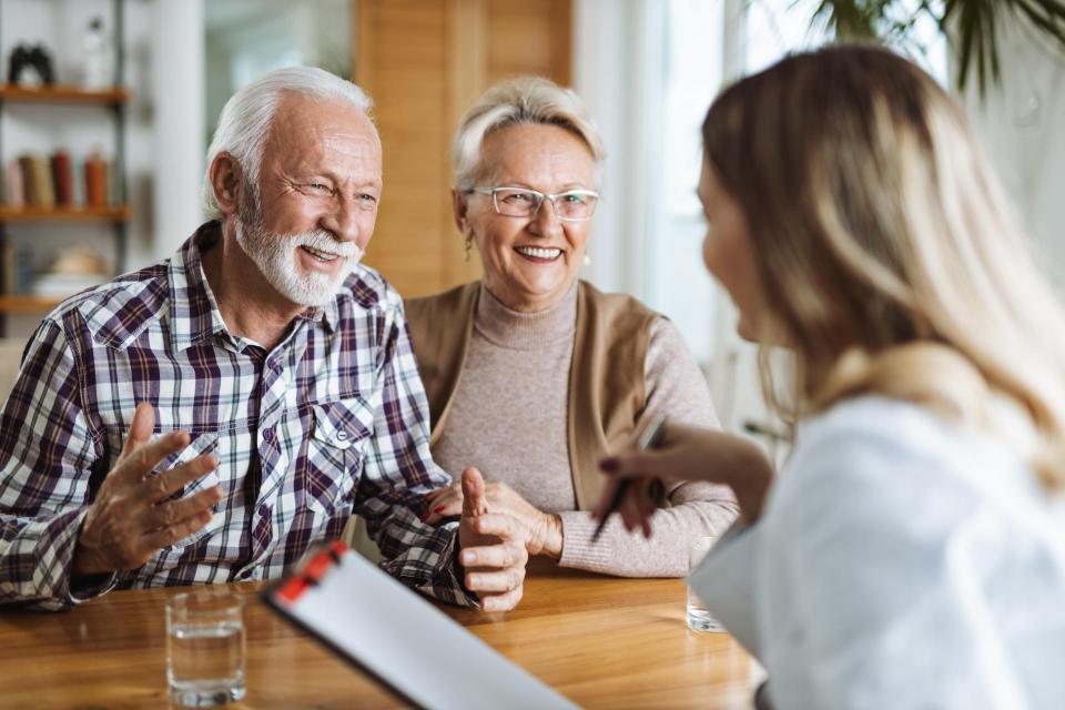 Happy senior couple talking with their female nurse at home