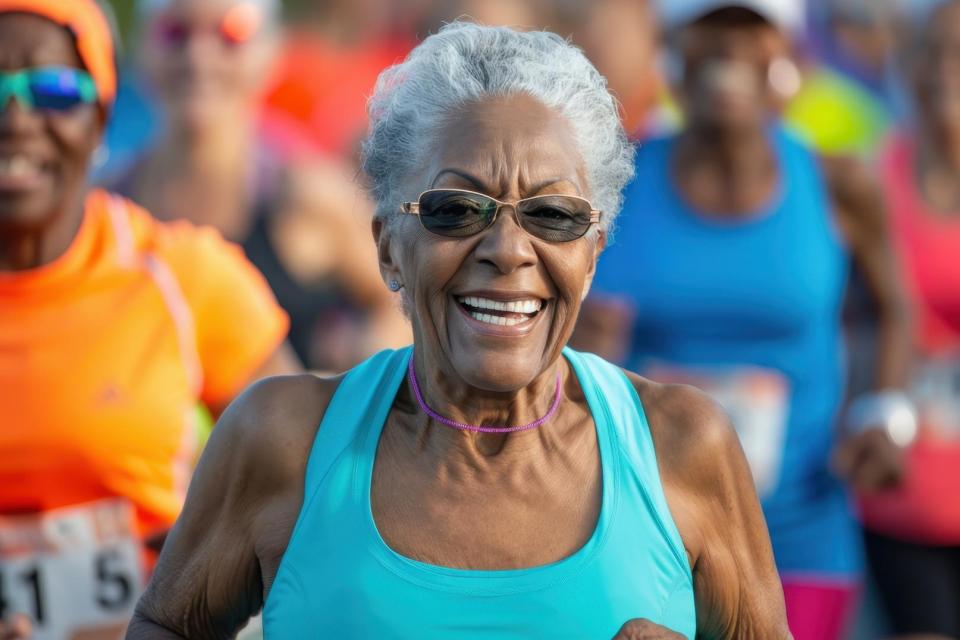 An elderly woman runs energetically in a community 5K event surrounded by enthusiastic runners